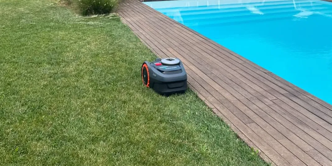 Robot rasaerba al lavoro sul prato accanto alla piscina