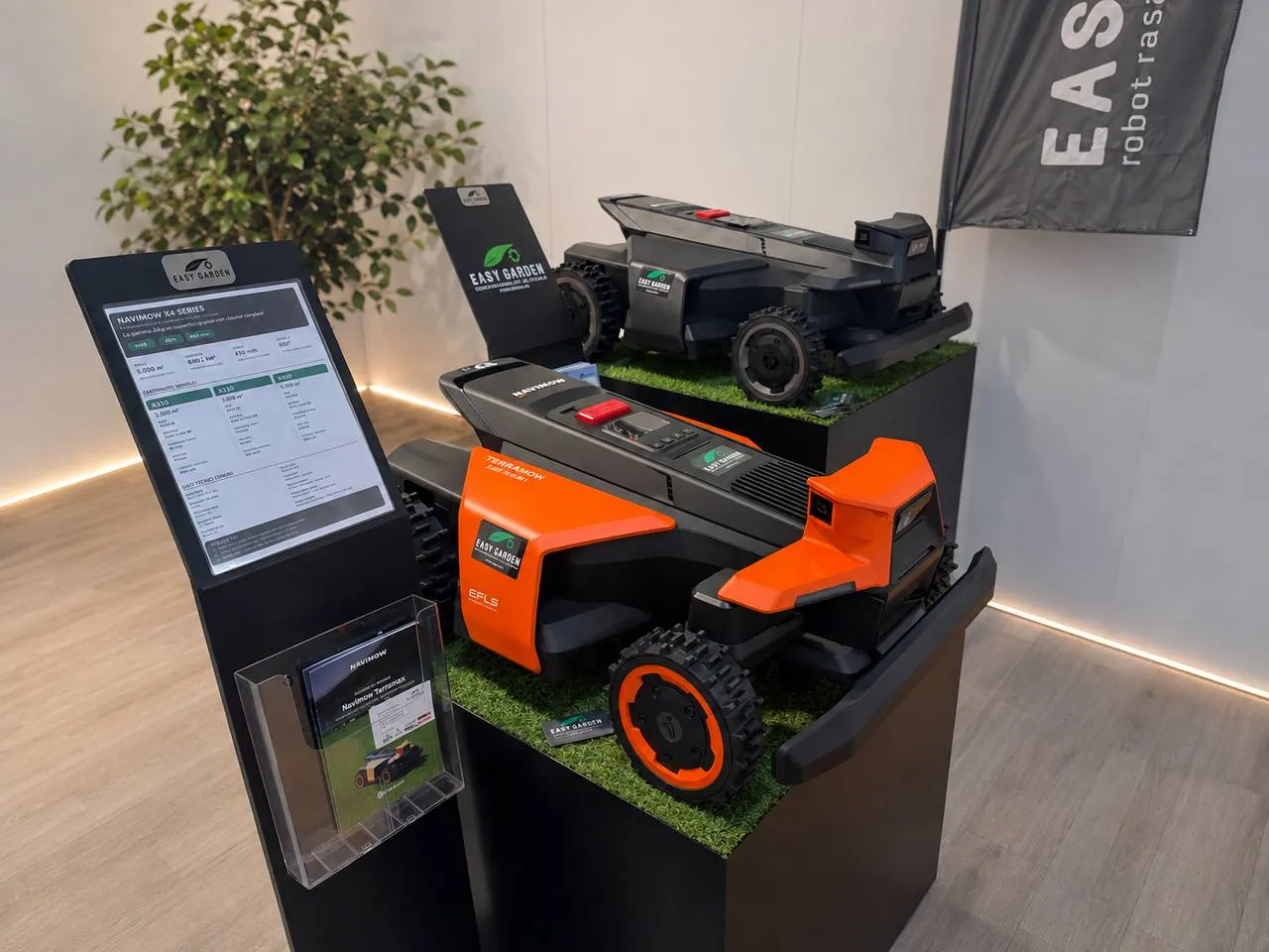 Robot rasaerba nuovi esposti in negozio su piedistalli con l'erba sintetica, accanto al totem con la scheda tecnica e i depliant